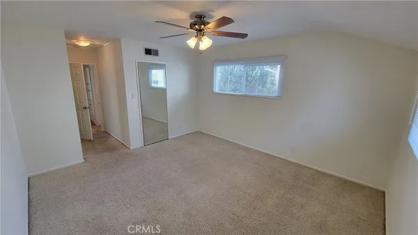 an empty room with closet and a ceiling fan