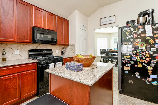 a kitchen with stainless steel appliances granite countertop a stove top oven a sink dishwasher and a microwave oven with large trees