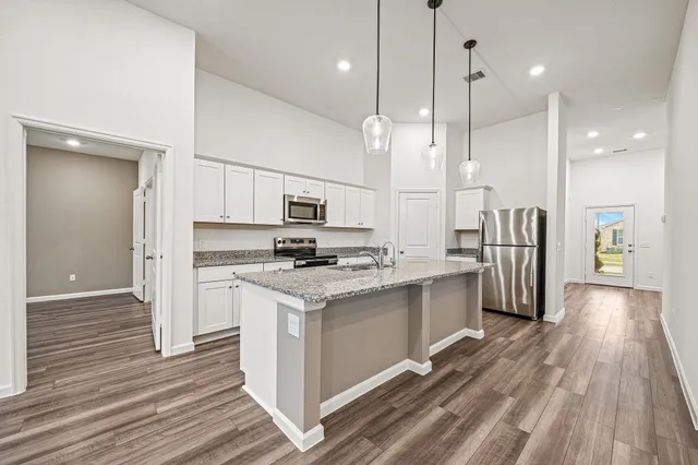 a kitchen with stainless steel appliances a stove top oven a sink cabinets and a wooden floor