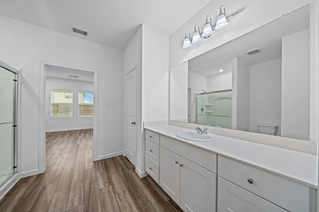a en suite bathroom with a granite countertop double vanity sink and a mirror