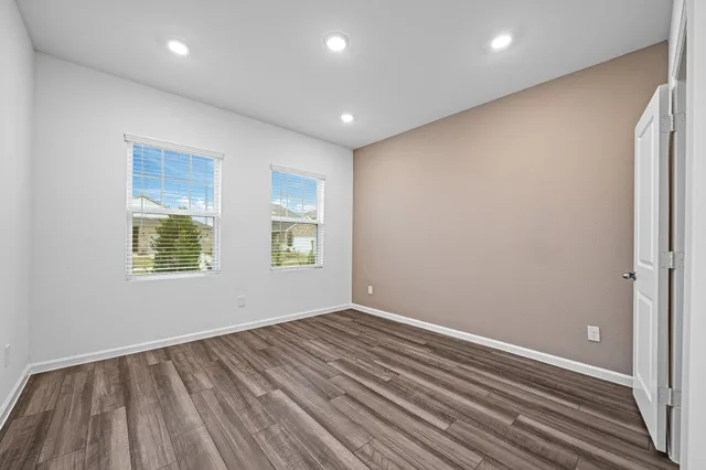 an empty room with wooden floor and windows
