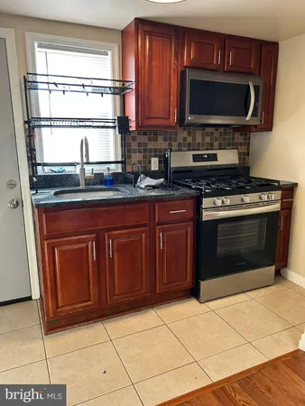 a kitchen with granite countertop a stove top oven microwave and cabinets