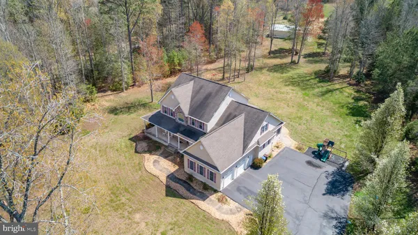 an aerial view of a house with a yard and large tree