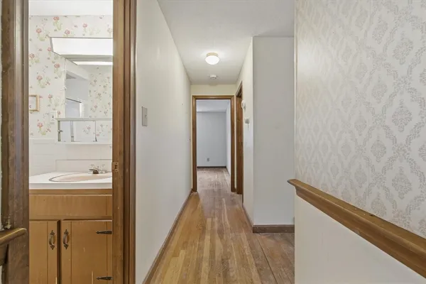 a view of a hallway with wooden floor and a bathroom
