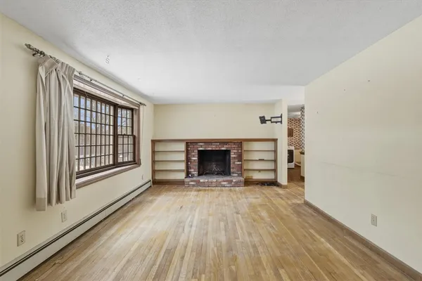 a view of an empty room with a fireplace and a window