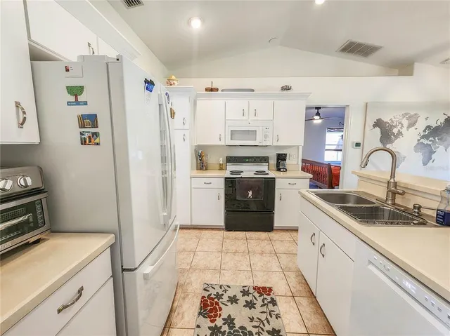 a kitchen with granite countertop a sink stainless steel appliances and white cabinets