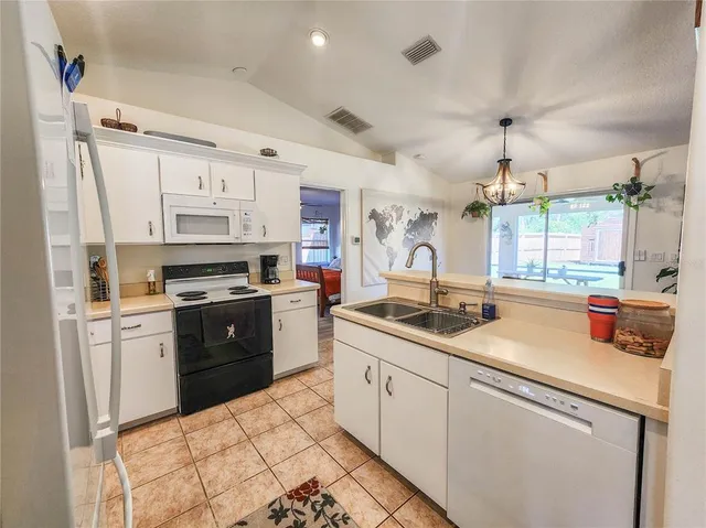 a kitchen with granite countertop a refrigerator stove and sink