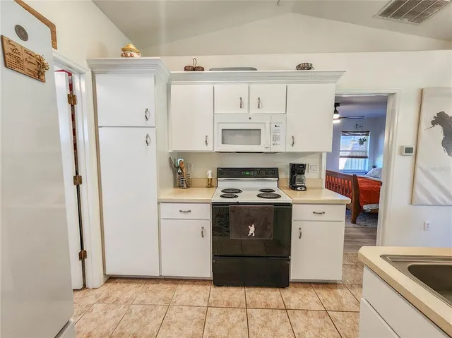 a view of a kitchen with stainless steel appliances granite countertop a sink dishwasher and a stove with large cabinets