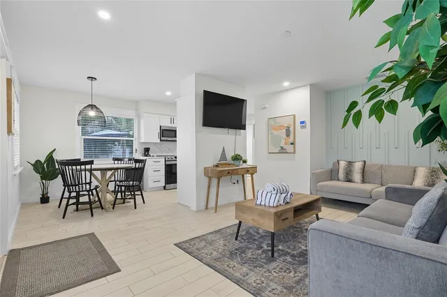 a living room with furniture potted plant and kitchen view
