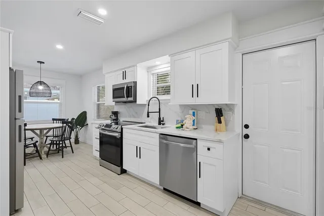 a kitchen with white cabinets and stainless steel appliances