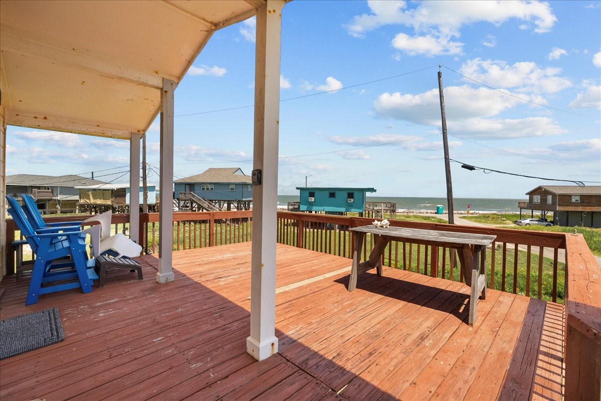 819 Seashell Drive Surfside Beach, TX 77541 - Photo 11 of 36 This photo showcases a spacious wooden deck with ocean views, ideal for relaxing or entertaining. The deck features comfortable seating and a rustic table, offering a serene coastal atmosphere.