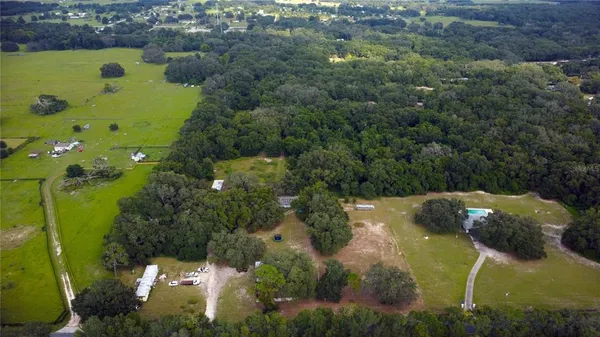 an aerial view of a residential houses with outdoor space and trees
