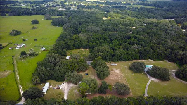 an aerial view of a residential houses with outdoor space and trees