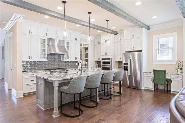 a kitchen with stainless steel appliances granite countertop a table chairs stove and white cabinets