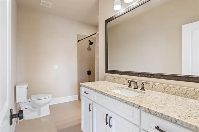 a bathroom with a granite countertop sink a toilet and a mirror
