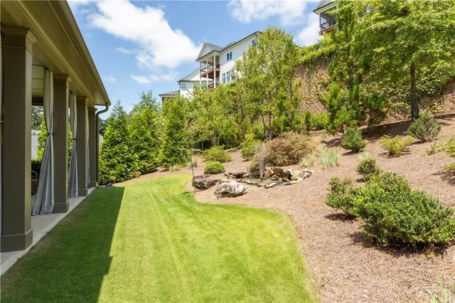 a view of a backyard with table and chairs plants and large trees