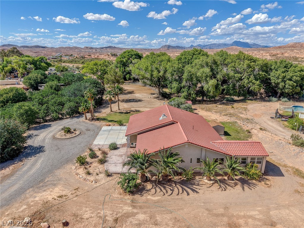 1950 Bowman Road Logandale, NV 89021 - Photo 65 of 81 An aerial perspective reveals a serene desert oasis with a single-story home amidst verdant trees and distant mountains.