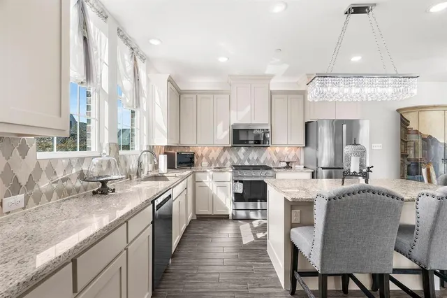 a large white kitchen with stainless steel appliances granite countertop a sink and cabinets