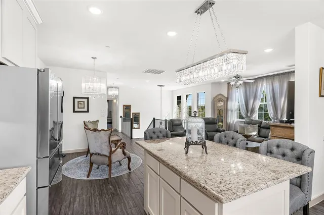 a kitchen with stainless steel appliances granite countertop a stove top oven a sink dishwasher a dining table and chairs with wooden floor