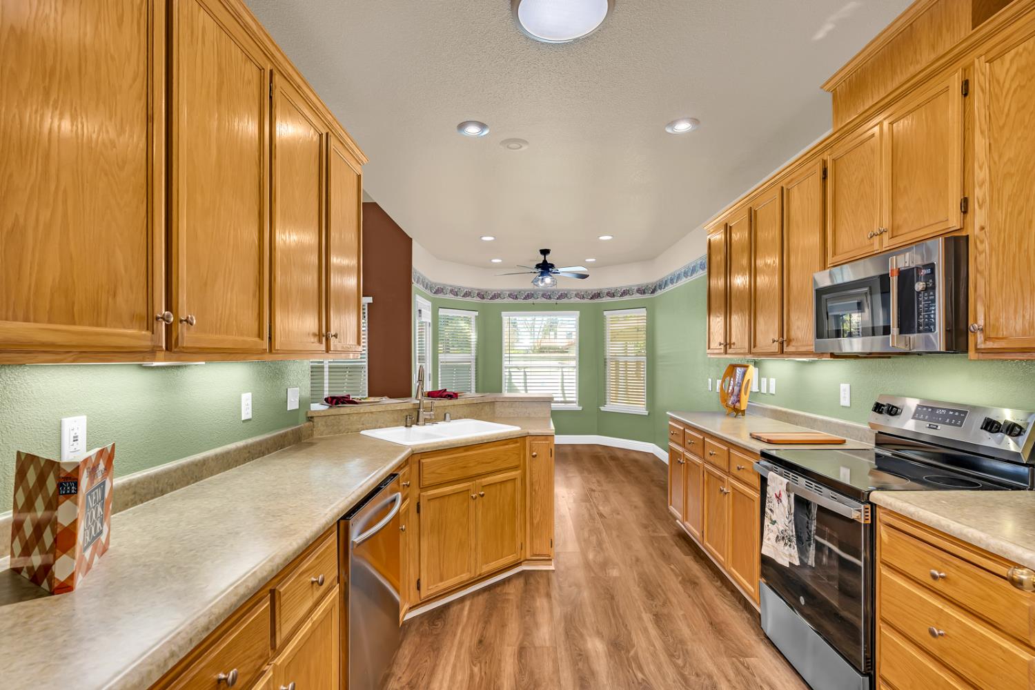 3877 Pintail Court Merced, CA 95340 - Photo 8 of 42 a kitchen with a sink a counter top space cabinets stainless steel appliances and a large window