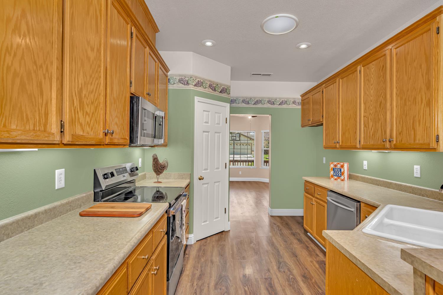 3877 Pintail Court Merced, CA 95340 - Photo 9 of 42 a kitchen with stainless steel appliances granite countertop a sink a stove cabinets counter space and wooden floor