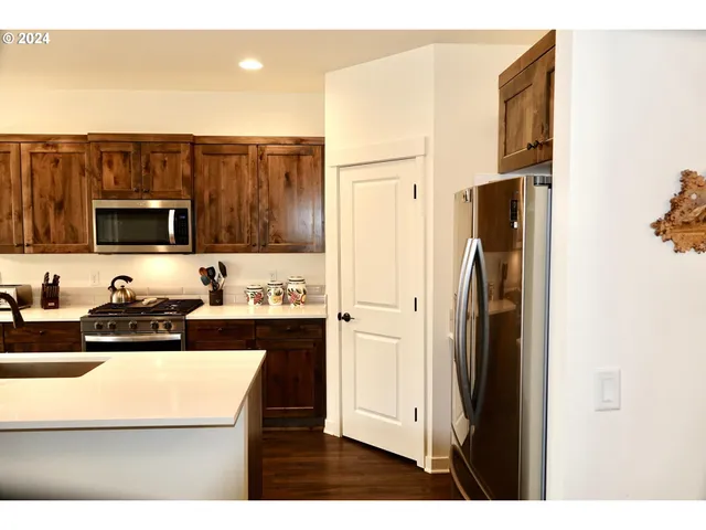 a kitchen with stainless steel appliances granite countertop a refrigerator a stove a sink and a microwave with wooden floor