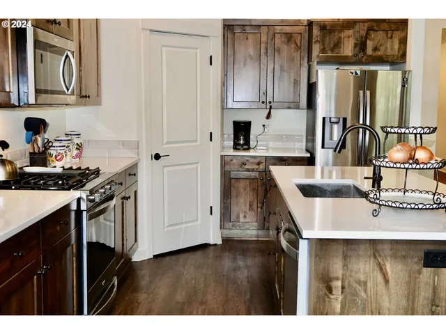 a kitchen with kitchen island granite countertop a sink cabinets and stainless steel appliances