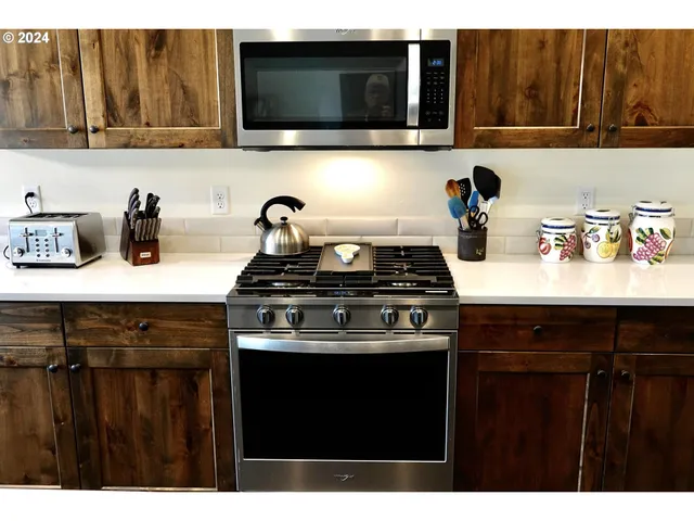 a kitchen with kitchen island stainless steel appliances a sink a stove and a microwave