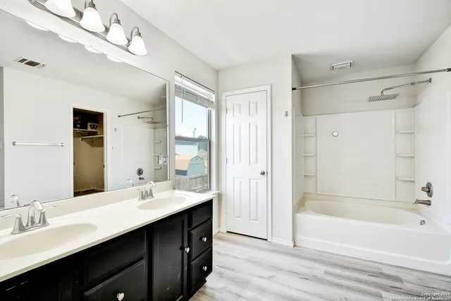 a bathroom with a double vanity sink mirror and bathtub