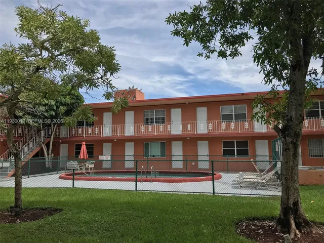 a front view of a house with a garden and trees