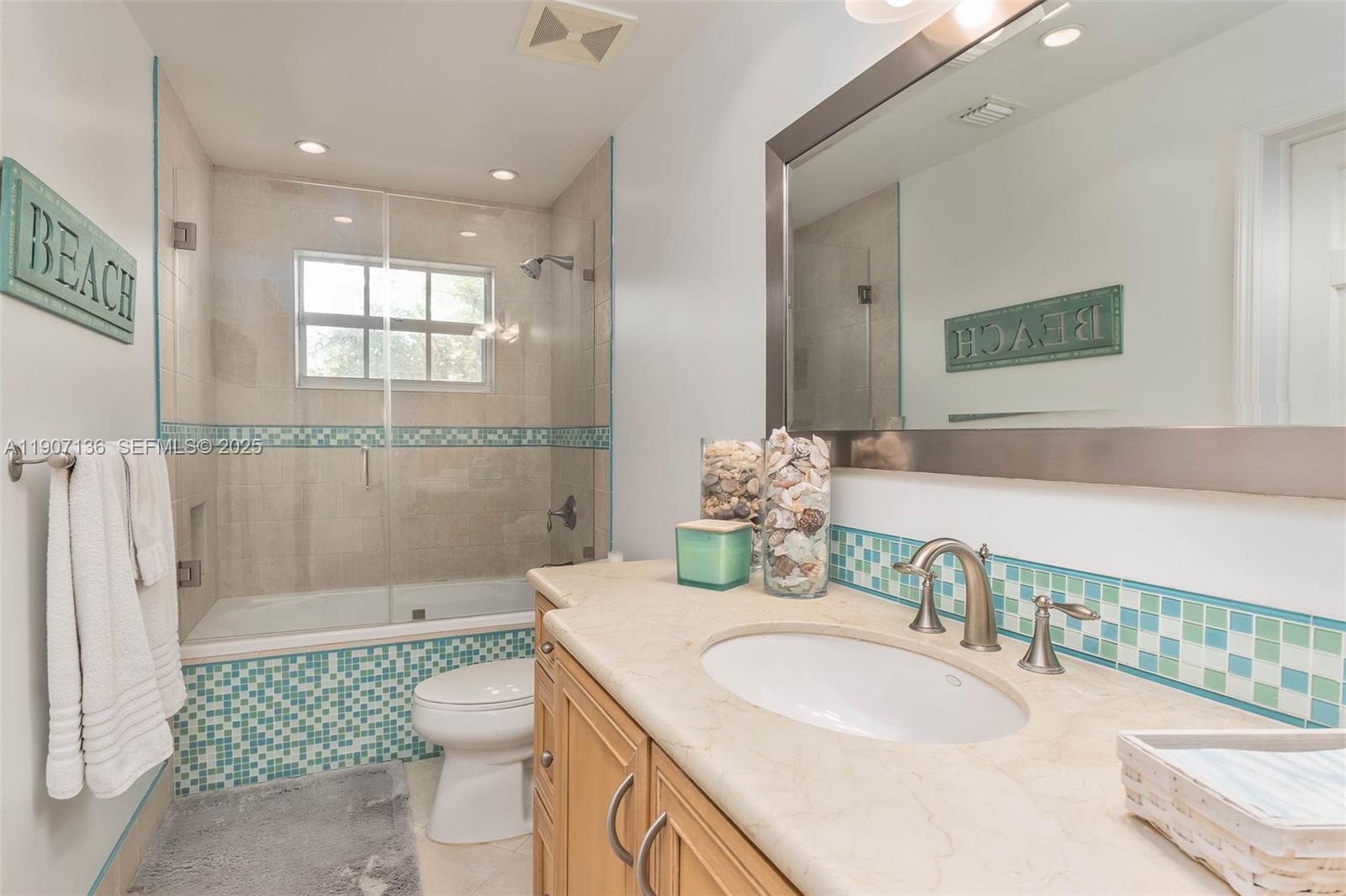 9240 Southwest 69th Court Pinecrest, FL 33156 - Photo 17 of 32 a bathroom with a granite countertop sink a mirror and a toilet