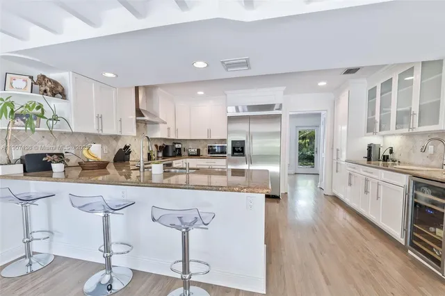 a kitchen with stainless steel appliances granite countertop a stove a sink a refrigerator and cabinets with wooden floor