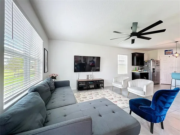 a living room with furniture a flat screen tv and a large window