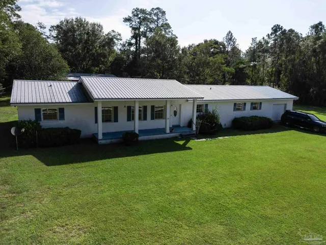 a front view of a house with garden and trees