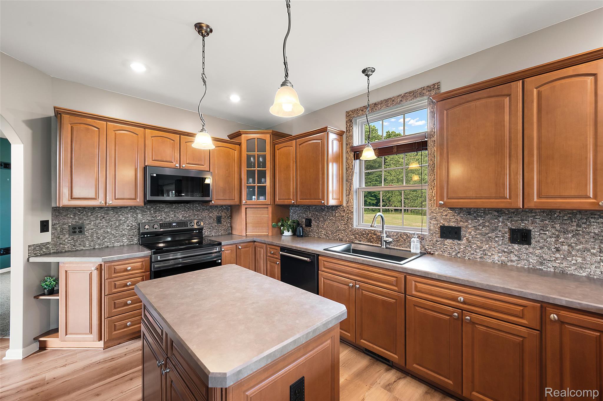 5035 Hidden Ridge Road Metamora, MI 48455 - Photo 21 of 65 Kitchen featuring wood cabinetry, a center island with countertop, mosaic tile backsplash, black appliances, and a window above the sink