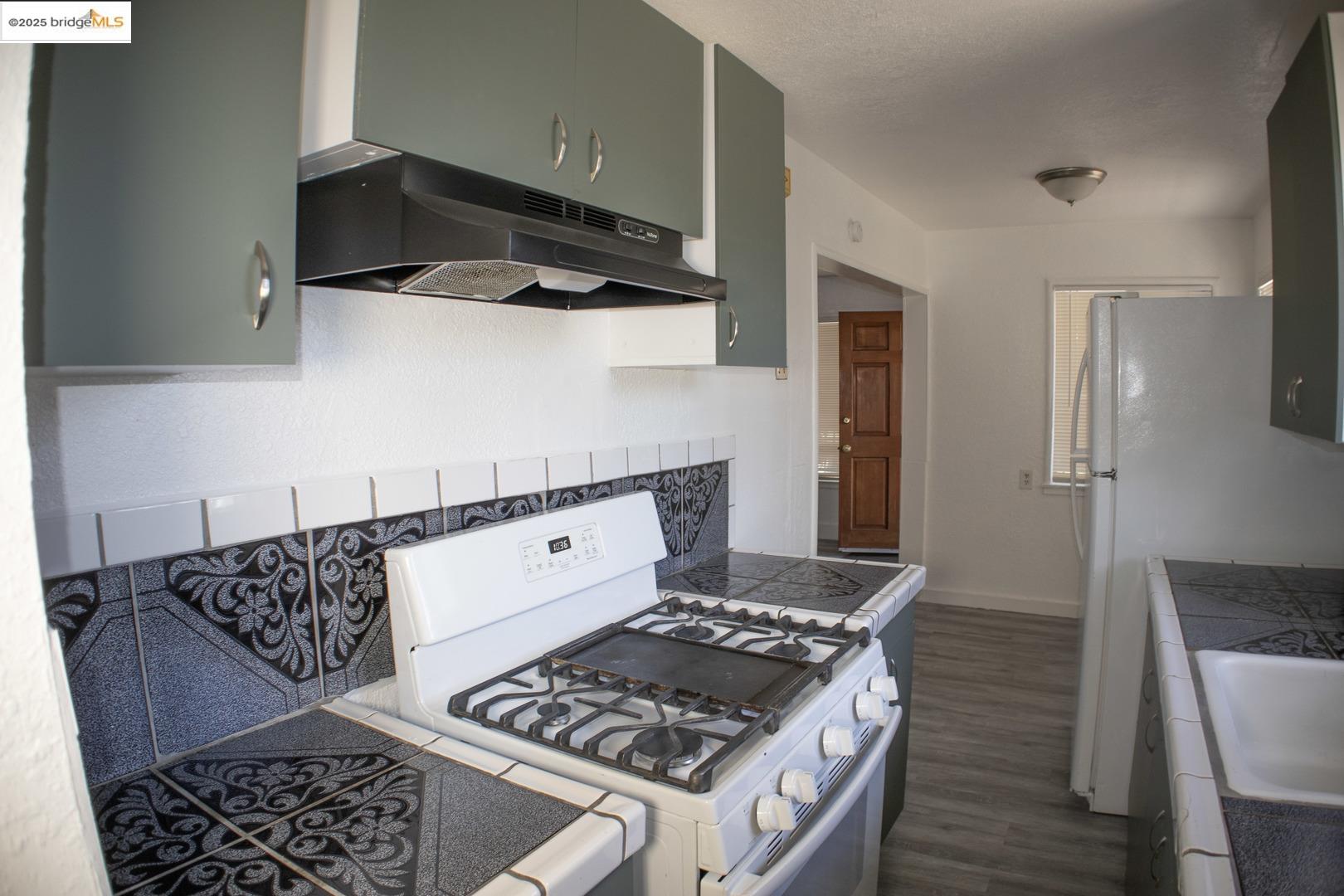 6921 Flora Street Oakland, CA 94621 - Photo 11 of 22 a kitchen with wooden cabinets and a stove top oven