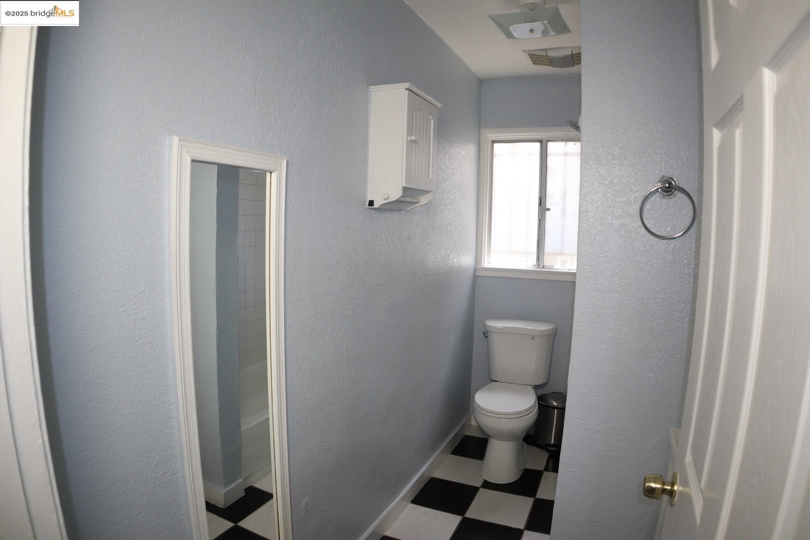 6921 Flora Street Oakland, CA 94621 - Photo 15 of 22 a bathroom with a toilet and a shower curtain