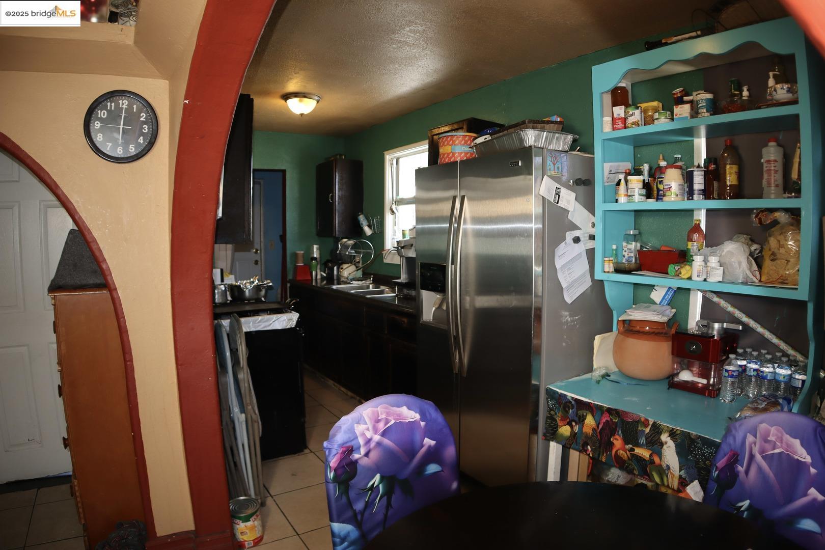 6921 Flora Street Oakland, CA 94621 - Photo 19 of 22 a kitchen with stainless steel appliances granite countertop a refrigerator a stove a microwave and a dining table with wooden floor