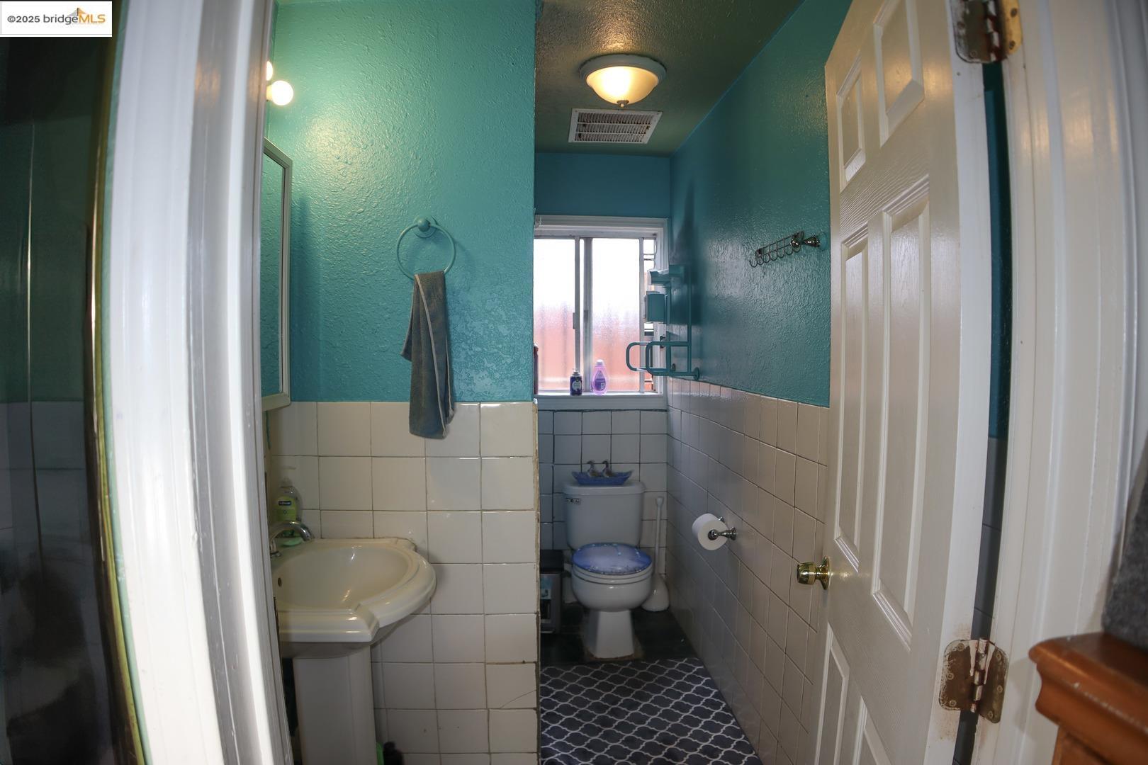 6921 Flora Street Oakland, CA 94621 - Photo 21 of 22 a bathroom with a toilet and a mirror
