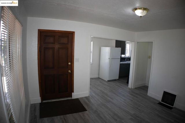 a view of a kitchen with refrigerator and wooden floor