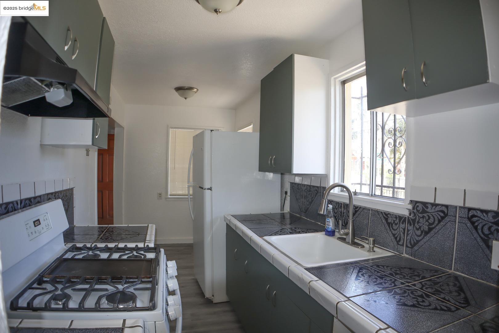 6921 Flora Street Oakland, CA 94621 - Photo 10 of 22 a kitchen with a sink stove and refrigerator