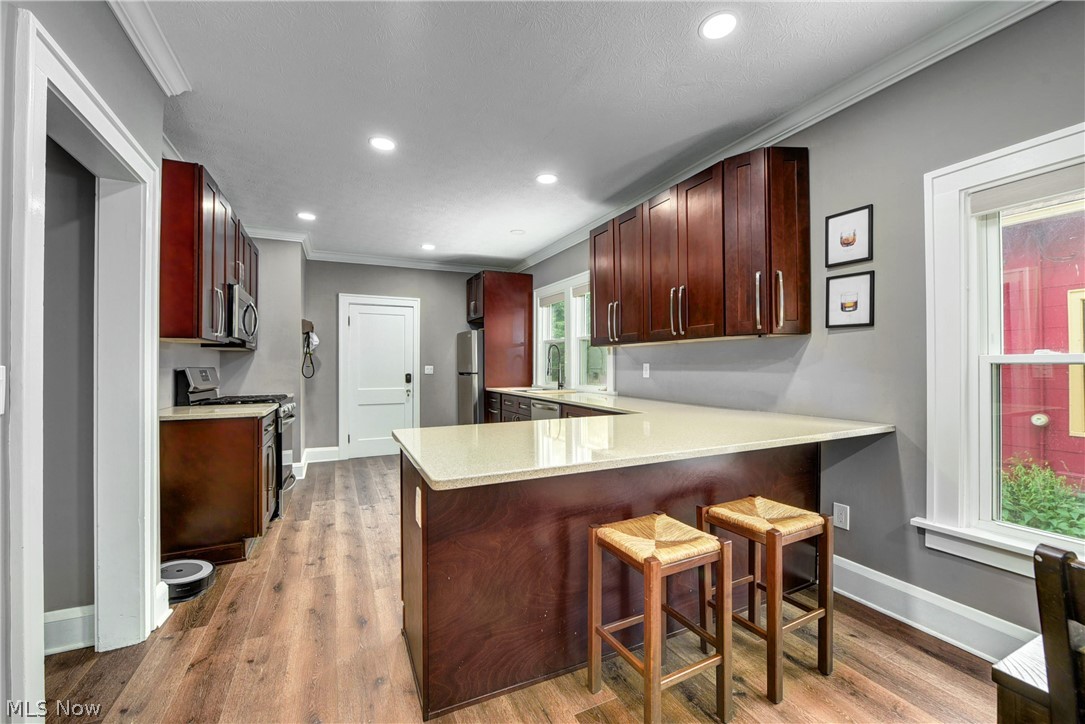 7408-7410 Rutledge Avenue Cleveland, OH 44102 - Photo 9 of 46 Kitchen with appliances with stainless steel finishes, hardwood / wood-style floors, and a breakfast bar