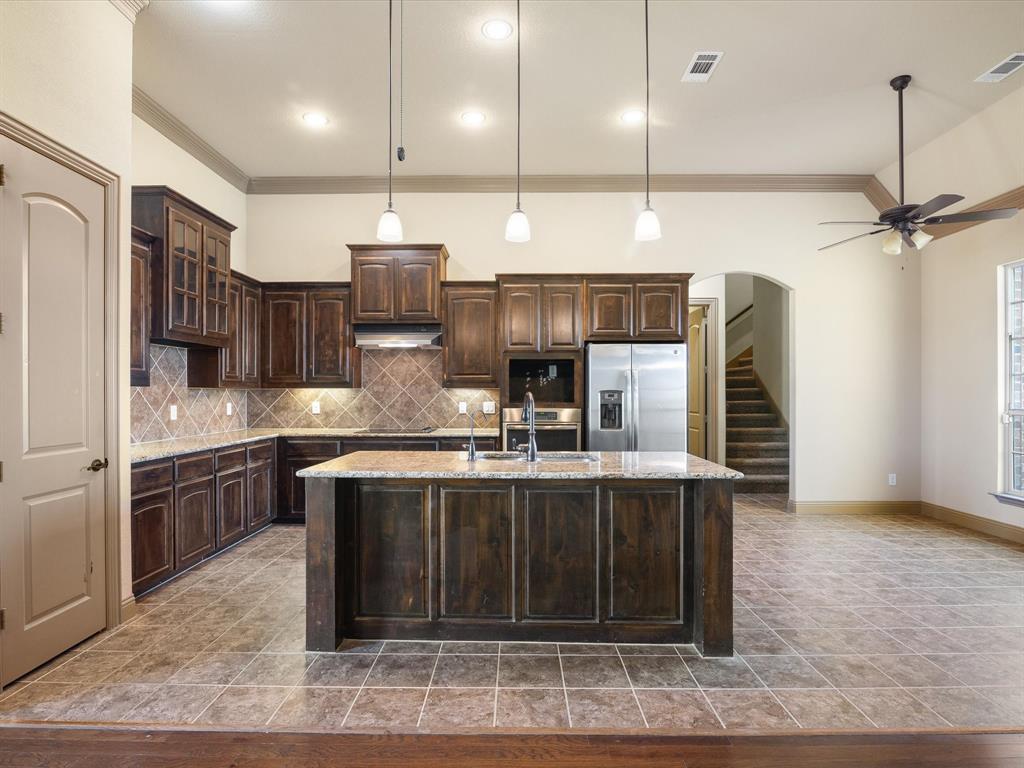 105 Timothy Lane Decatur, TX 76234 - Photo 1 of 1 Kitchen featuring ornamental molding, under cabinet range hood, stainless steel fridge, and a sink