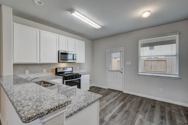 a kitchen with stainless steel appliances granite countertop a sink stove and microwave