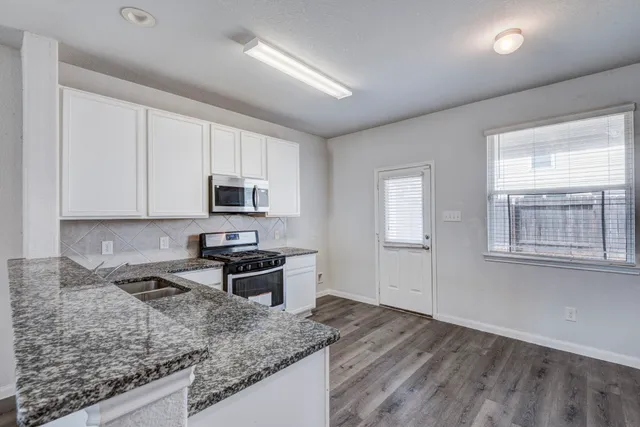 a kitchen with stainless steel appliances granite countertop a sink stove and microwave