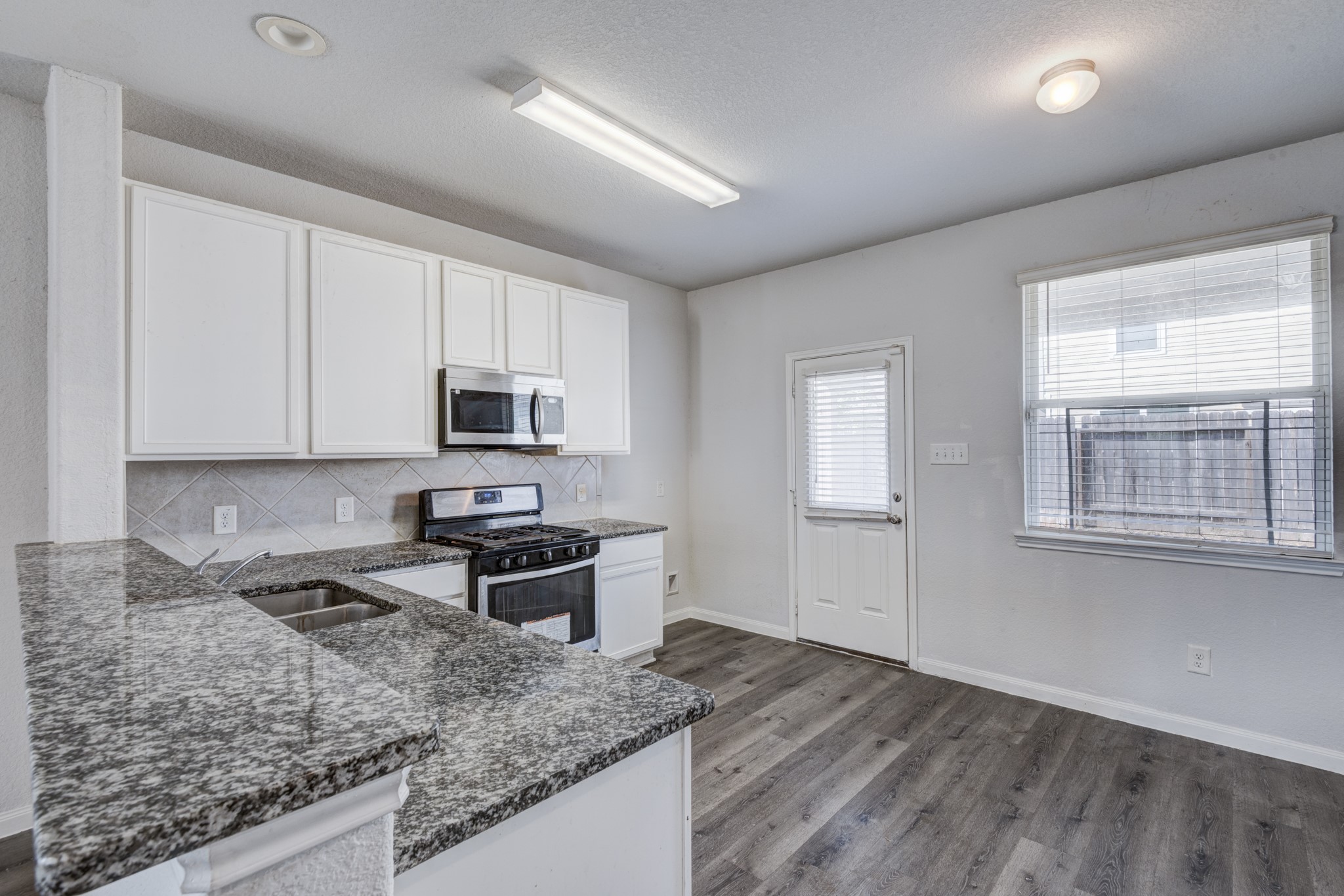 5011 Blue Jacaranda Way Spring Spring, TX 77373 - Photo 16 of 32 a kitchen with stainless steel appliances granite countertop a sink stove and microwave