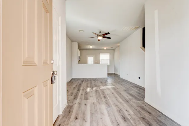 a view of a hallway with wooden floor and a bathroom