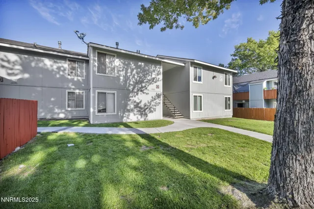 a backyard of a house with table and chairs and a large tree