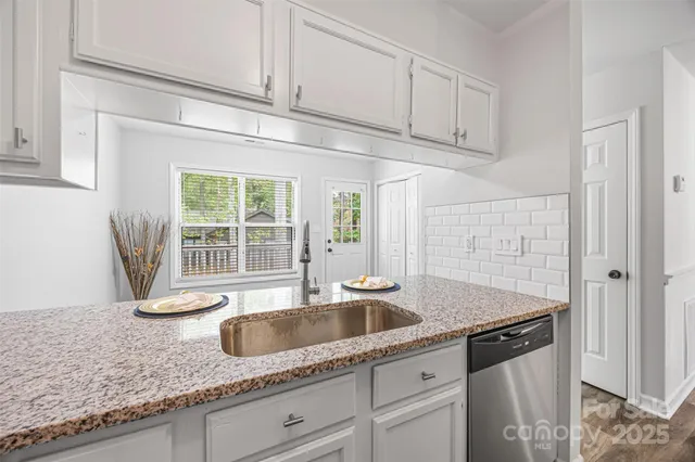 a kitchen with granite countertop a sink a stove and cabinets
