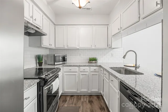 a kitchen with white cabinets a sink stove and white stainless steel appliances